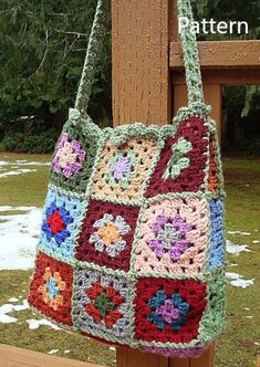 a multicolored crocheted bag hanging from a wooden post