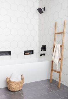 a bathroom with white hexagonal tiles and wooden ladder in the bathtub area