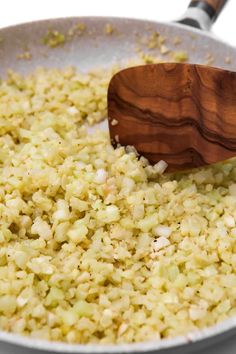 a pan filled with rice and a wooden spoon on top of the stove burner