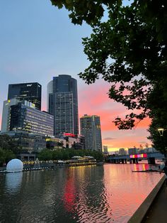 the city skyline is lit up at dusk as seen from across the river in front of tall buildings