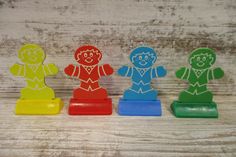 three wooden toy figures in different colors and sizes