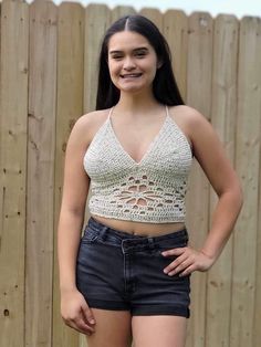 a woman standing in front of a fence wearing short shorts and a cropped top