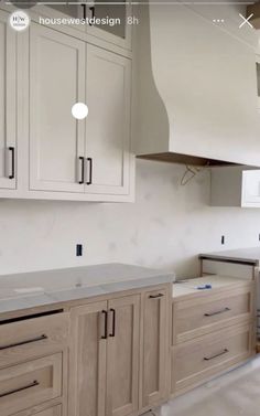 an empty kitchen with white cabinets and gray counter tops on the island in front of the stove