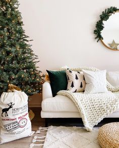 a white couch sitting next to a christmas tree in a living room under a mirror