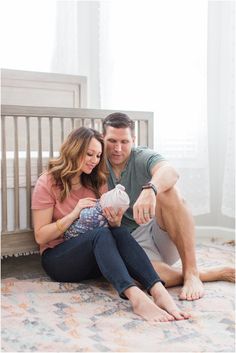 a man and woman are sitting on the floor with their baby