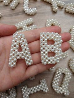 someone is holding letters made out of pearls