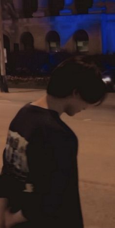 a young man riding a skateboard down a street next to a tall blue building