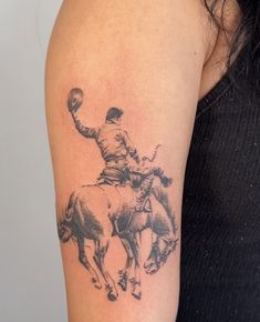 a woman with a tattoo on her arm is riding a horse and holding a lasso