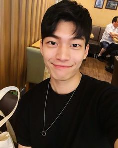 a young man is smiling and posing for the camera in front of some people at a restaurant