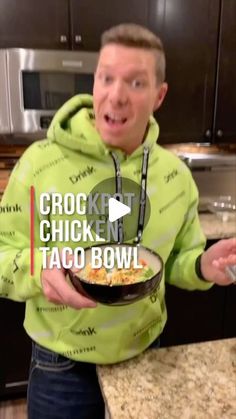 a man in a green hoodie is holding a bowl of chicken taco bowls