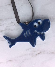 a blue ceramic shark ornament hanging on a lanyard