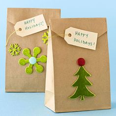 two brown paper bags with green and red decorations on them, one has a tag that says happy holidays