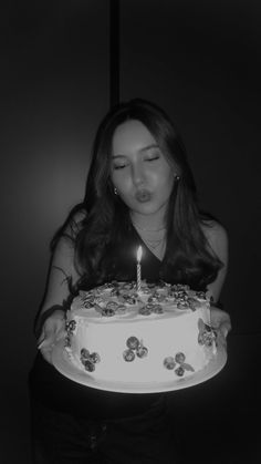 a woman blowing out the candles on her birthday cake while holding it in her hands