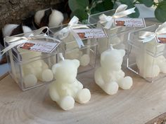 four clear boxes with small white candles in them