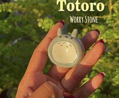 a person holding a tiny toy in their hand with the words totoro on it