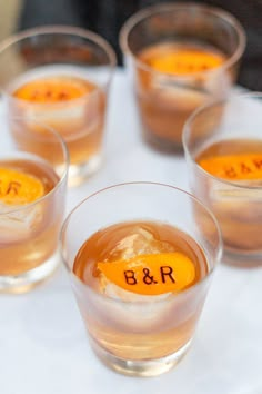 four glasses filled with drinks sitting on top of a white tablecloth covered in writing