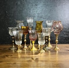 an assortment of glass vases sitting on top of a wooden table