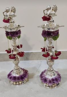 two silver candlesticks with flowers on them