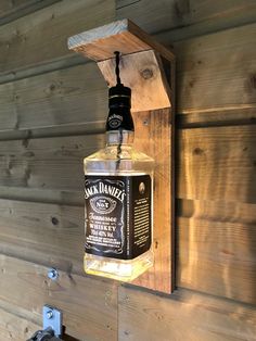 a bottle of jack daniels sitting on top of a wooden shelf next to a wall