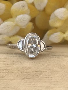 a close up of a ring on a wooden surface with yellow flowers in the background