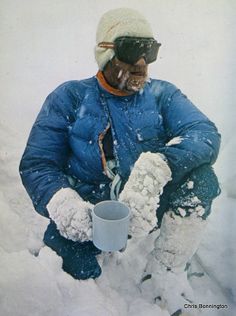 a man sitting in the snow holding a cup