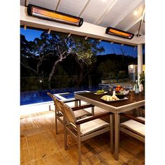 an outdoor dining area with table, bench and heater on the wall above it