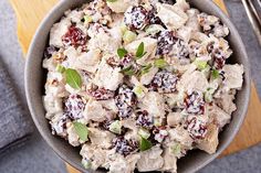 a bowl filled with chicken salad on top of a wooden cutting board next to silverware