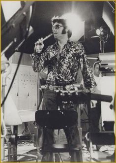 an old photo of a man holding a microphone in his right hand and standing on a stool