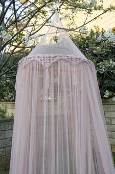 a pink canopy bed sitting in the middle of a garden