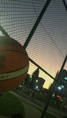 a basketball sitting on top of a field next to a fence