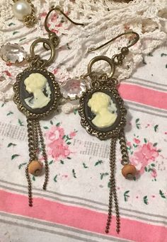 "Vintage Black Cameo Pierced Earrings 1980s... Cream on Black Plastic Cameos set in bronze colored metal , dangle along with 3 chains , one of which has a bead at the bottom and a dangling faceted clear bead .. all hang from fish hook type ear wires ! About 3\" drops Very light weight! Great condition We ship to USA only Fast Shipping BLESSINGS! check out our other items! http://www.etsy.com/shop/oldstuffetc" Black Cameo, Black Plastic, Pierced Earrings, Bronze Color, Fish Hook, Earings Piercings, Ear Wires, Vintage Black, Etsy Earrings