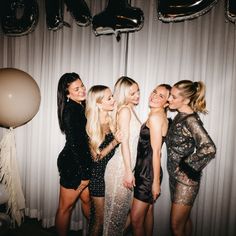 four beautiful young women standing next to each other in front of balloons and streamers