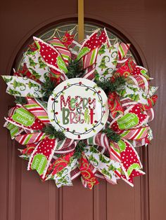 a christmas wreath hanging on the front door with merry brush written in white and green