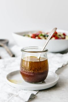 a glass jar filled with food sitting on top of a white plate next to a bowl