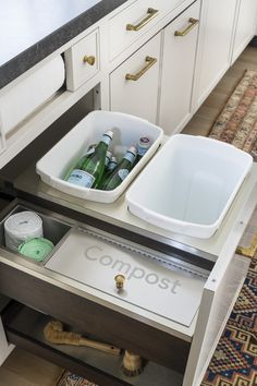 an open drawer in a kitchen with two containers on the bottom and one filled with bottles