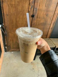 a person holding up a plastic cup with a straw in it