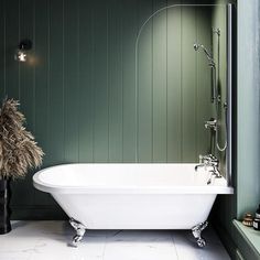 a white bath tub sitting in a bathroom next to a window with green painted walls