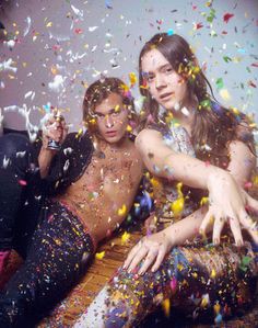 two people sitting on the floor surrounded by confetti