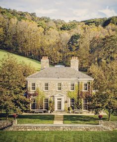 a large stone house surrounded by trees and grass