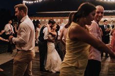 a group of people standing on top of a wooden floor next to each other at a wedding