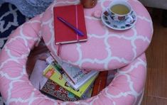 a pink chair with books and a cup of coffee sitting on it's seat