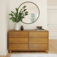 a wooden dresser topped with a mirror next to a plant