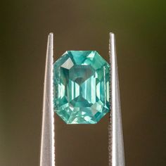 an emerald is sitting on top of three silver poles, with another one in the background