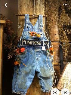 an old pair of denim overalls with flowers on them hanging from a clothes rack