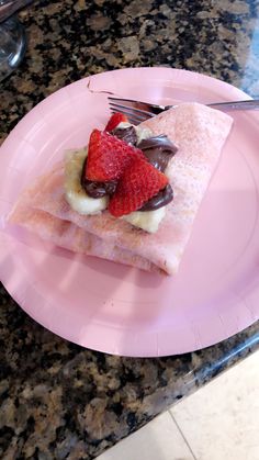 a pink plate topped with two slices of cake and strawberries on top of it