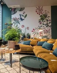 a living room filled with lots of furniture next to a tall wall covered in plants