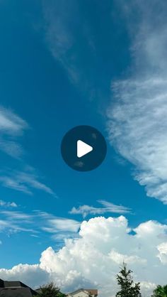 a blue sky with clouds and a white house in the foreground that has a play button on it