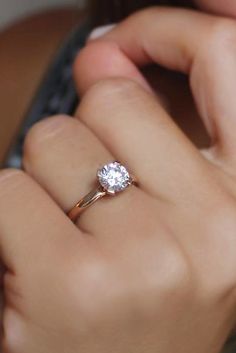 a close up of a person's hand holding a ring with a diamond on it