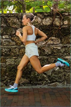 a woman running down a brick sidewalk next to a stone wall