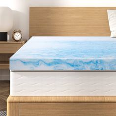 an image of a bed with blue water on the bottom and white mattress topper